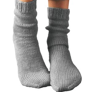 May include: A pair of gray knitted socks. The socks are a solid gray color and have a ribbed cuff at the top. The socks are made of a thick, warm material and are designed to be worn on the feet.