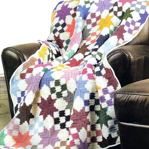 May include: A colorful crocheted throw blanket with a star pattern in shades of pink, purple, blue, green, yellow, and brown. The blanket is draped over a brown leather armchair.
