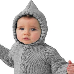 May include: A light gray knitted cardigan featuring a pointed hood, long sleeves, and a front button closure with four matching circular buttons. The garment is crafted with a ribbed texture along the cuffs, hem, and hood edge, providing a consistent look.