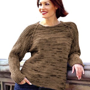 May include: A brown knitted sweater with a round neckline and long sleeves. The sweater has a subtle marled effect.