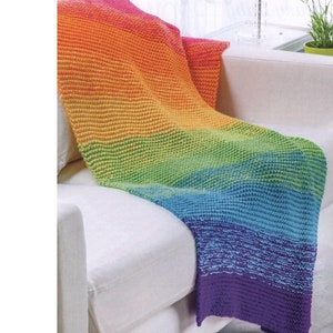 May include: A rainbow colored crochet throw blanket draped over a white couch.
