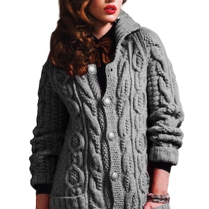 May include: A grey cable-knit cardigan with a shawl collar and large, round buttons. The long-sleeved sweater features a textured pattern and two front pockets. The cardigan is a medium grey colour.