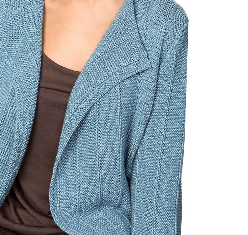 May include: A light blue knitted cardigan with a shawl collar. The cardigan is made of a soft, textured fabric.