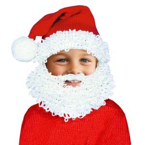 May include: A child wearing a red Santa hat with a white pom-pom and a white fluffy beard.