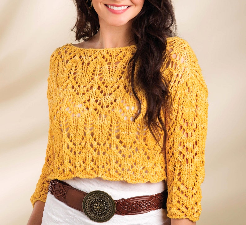 Pode incluir: Um top de croch&ecirc; amarelo com um padr&atilde;o de renda delicado. O top tem um decote largo e redondo e mangas tr&ecirc;s quartos. &Eacute; usado com um cinto de couro marrom com uma fivela grande e adornada.