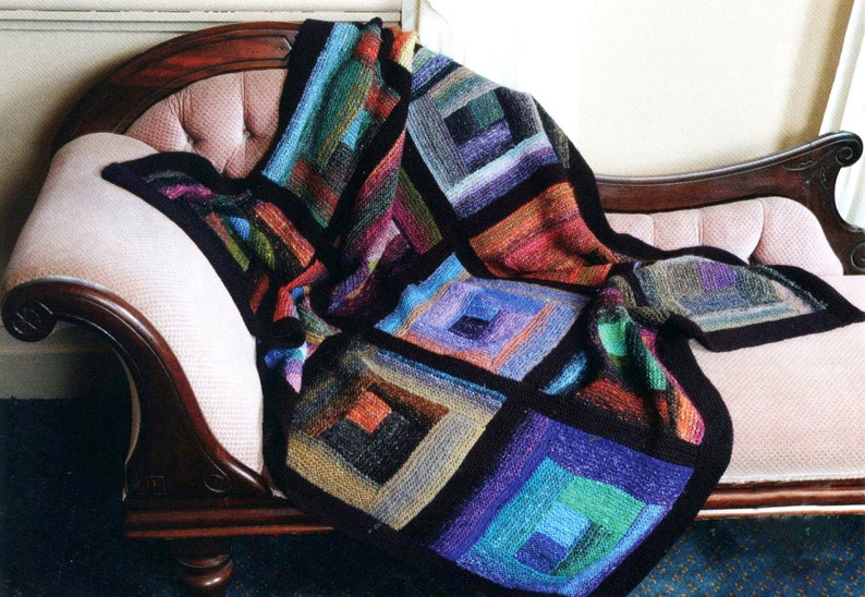 May include: A colorful knitted throw blanket with a geometric pattern of squares in shades of blue, green, red, and brown. The blanket is draped over a chaise lounge.