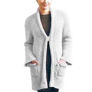 May include: A long-sleeved white cardigan with a shawl collar and two pockets. The cardigan is made of a soft, textured knit fabric.