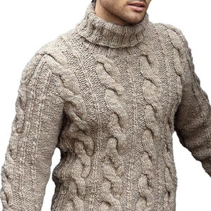 Puede incluir: Un jersey beige de cuello alto y punto trenzado. El jersey presenta un tejido grueso y texturizado con intrincados patrones de trenzas en el pecho y las mangas. El cuello alto está doblado. El estilo es clásico y cálido, adecuado para el invierno.