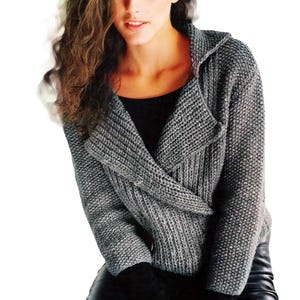 May include: A grey knitted cardigan with a hood and a wrap-around front. The cardigan is made of a soft, textured yarn.