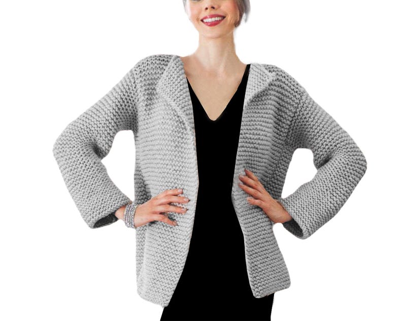 May include: A gray knitted cardigan with a shawl collar and long sleeves. The cardigan is open in the front and has a relaxed fit.