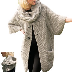 Op de afbeelding: Een lange, lichtgrijze gebreide cardigan met een kabelgebreide kraag en zakken. De cardigan heeft een knoopsluiting.