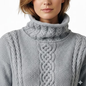 May include: A light grey cable-knit turtleneck jumper. The jumper has a high, ribbed collar and detailed cable patterns on the front and sleeves. The knitwear is a soft, neutral colour, suitable for various outfits.