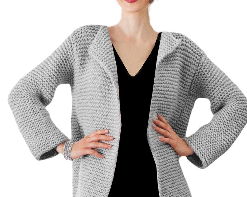 May include: A gray knitted cardigan with a long, open front and long sleeves. The cardigan is made of a soft, chunky yarn.