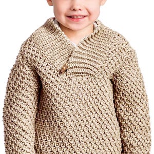 May include: A beige, textured knit sweater with a shawl collar and a wooden button closure. The sweater has a thick, woven appearance and long sleeves. The child is smiling.