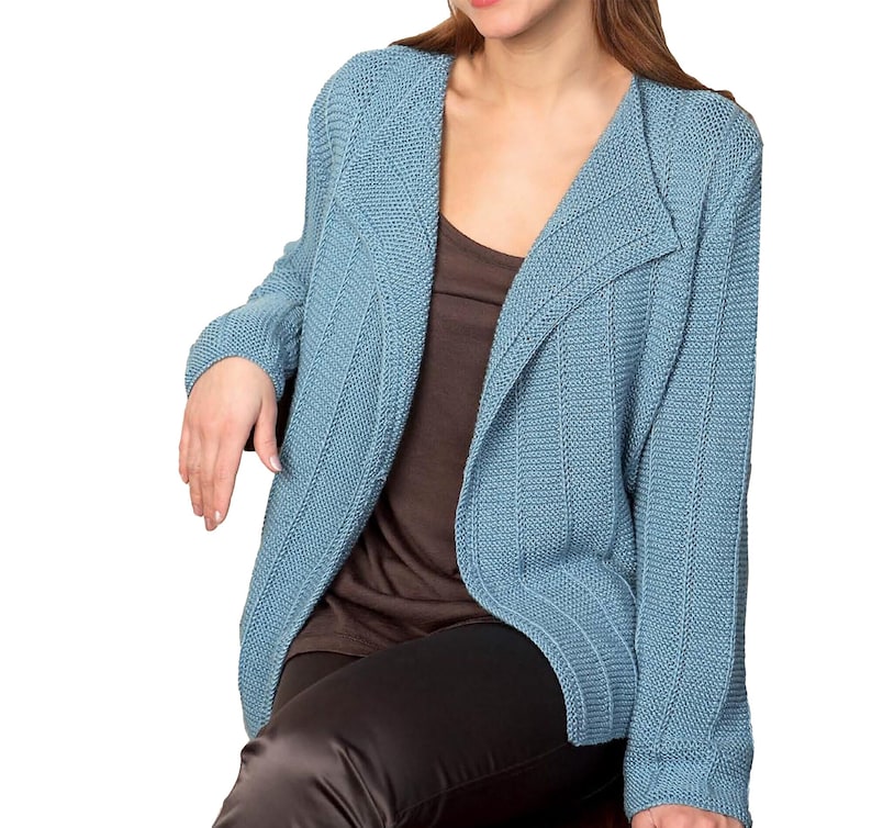May include: A light blue knitted cardigan with a shawl collar and long sleeves. The cardigan is open in the front and has a ribbed texture.