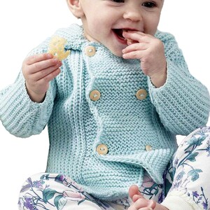 May include: A light blue, double-breasted, long-sleeved knit cardigan featuring a textured garter stitch pattern and four round, light-colored wooden buttons. The garment is paired with white pants decorated with a floral print in shades of blue and green.