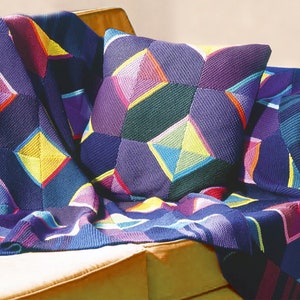 May include: A purple knitted throw blanket with a geometric pattern of colorful diamonds, draped over a couch with a matching pillow.