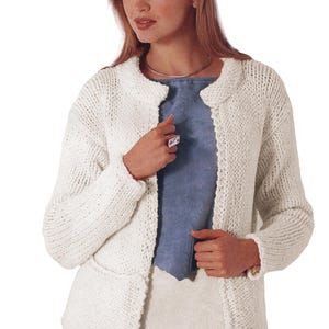 Puede incluir: Un cárdigan crema con frente abierto, cuello redondo y mangas largas. El suéter está hecho de una tela de punto gruesa y texturizada. La persona lleva una blusa azul debajo.