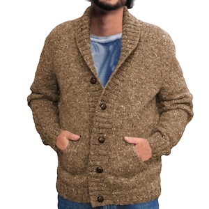 May include: A brown, button-down cardigan sweater with a shawl collar and two front pockets. The sweater has a speckled texture and is worn over a blue crew neck shirt. The buttons are a dark brown color.