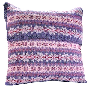 May include: A purple, pink and white knitted cushion with a snowflake pattern. The cushion is made from a soft, cosy material and is perfect for adding a touch of warmth and style to any room.