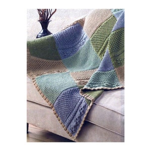以下が含まれることがあります： 緑、青、ベージュの色のパッチワーク模様のニットの毛布。毛布は折り畳んでソファにかけられています。