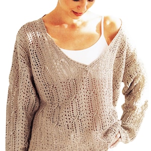 Puede incluir: Un suéter de tejido abierto de color marrón claro con cuello en V profundo. El suéter tiene mangas largas y un ajuste holgado y cómodo. El patrón de punto presenta un diseño delicado y de encaje. Una camiseta sin mangas blanca es visible debajo.