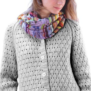 May include: A light gray, button-down cardigan with a textured, open-knit pattern. The cardigan is paired with a colorful, patterned scarf in shades of purple, orange, and green. The buttons are white.