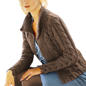 May include: A brown cable-knit cardigan with a wide collar. The sweater has a button closure and is worn over a blue top. The sleeves are long and the knit pattern is visible. The cardigan is a warm, casual garment.