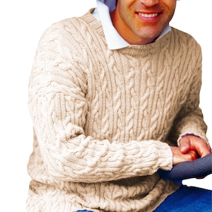 Puede incluir: Un suéter de punto de cable de color crema con cuello redondo.