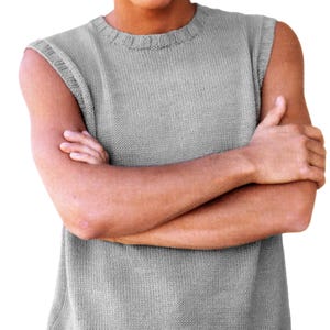May include: A light grey sleeveless knit sweater vest featuring a ribbed crew neckline and a matching ribbed hem. The garment is constructed with a smooth stockinette stitch pattern throughout the body and has finished armhole edges.