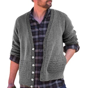 Può includere: Un cardigan grigio con bottoni e due tasche frontali. Il maglione è realizzato in un materiale a maglia spesso e ha uno scollo a V. La persona indossa una camicia a quadri sotto.