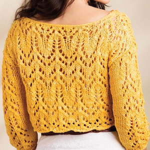 Pode incluir: Um su&eacute;ter de croch&ecirc; amarelo com um padr&atilde;o de renda. O su&eacute;ter tem um decote redondo e mangas tr&ecirc;s quartos.
