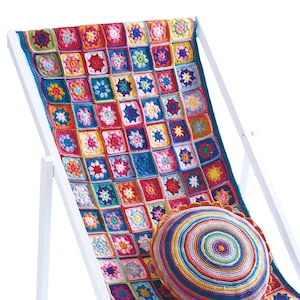 May include: A colorful, crocheted blanket with square patterns in various colors, draped over a white wooden deck chair. A round, crocheted pillow with concentric circles rests on the blanket. The blanket and pillow feature a variety of bright colors.