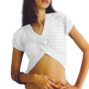 Puede incluir: Top corto de punto blanco con cuello en V y mangas cortas. El top tiene un detalle anudado en la parte delantera.