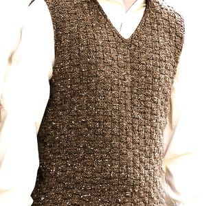 Puede incluir: Un chaleco marrón estilo tweed con cuello en V. El chaleco tiene una apariencia texturizada y se usa sobre una camisa de color claro. El estilo general es clásico y adecuado para combinar.