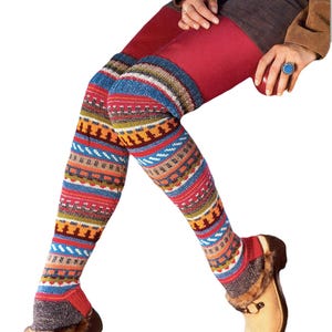 May include: A person wearing red leggings and patterned leg warmers with a variety of colours including blue, red, orange, and yellow. The person is also wearing tan clogs with fur trim.