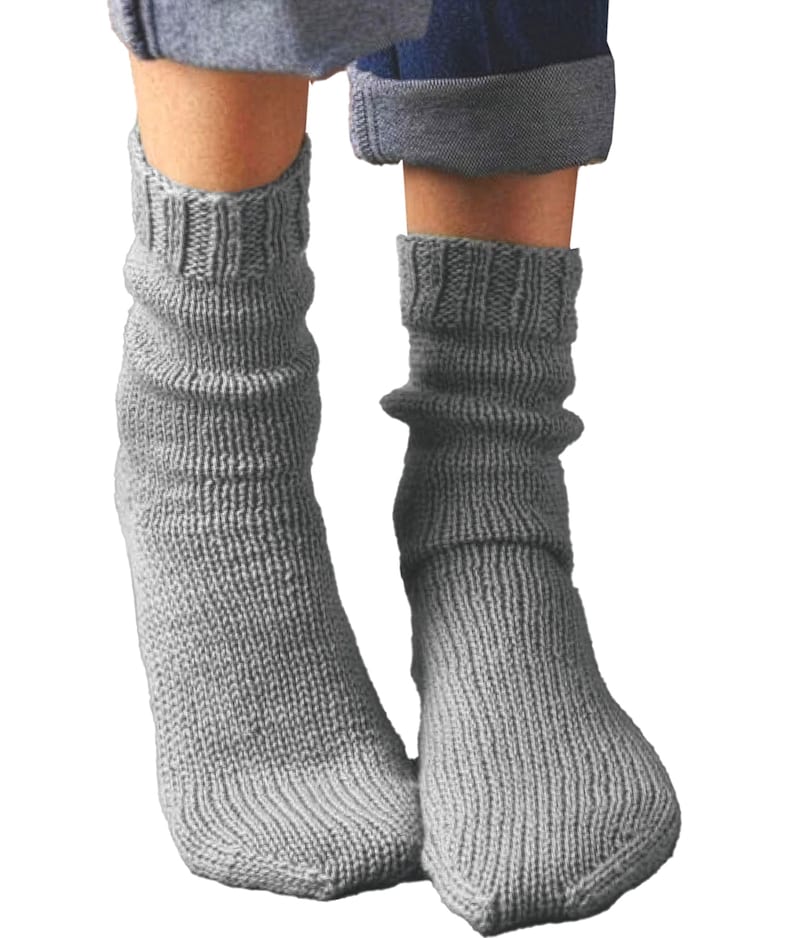 Puede incluir: Un par de calcetines de punto grises. Los calcetines son de color gris liso y tienen un pu&ntilde;o acanalado en la parte superior. Los calcetines est&aacute;n hechos de un material grueso y c&aacute;lido y est&aacute;n dise&ntilde;ados para usarse en los pies.