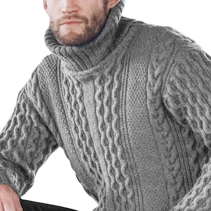 May include: A grey cable knit turtleneck sweater with a thick, textured knit. The sweater has a high neckline and a relaxed fit.