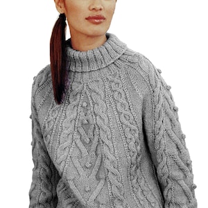 Puede incluir: Un suéter gris de punto trenzado con cuello alto. El suéter presenta un patrón texturizado con diseños de trenzas verticales y pequeñas bolitas. Las mangas y el cuerpo tienen un ajuste holgado, adecuado para climas más fríos. El diseño general es clásico y acogedor.