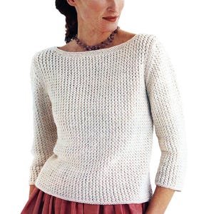 Puede incluir: Un suéter de punto blanco con cuello redondo y mangas largas.