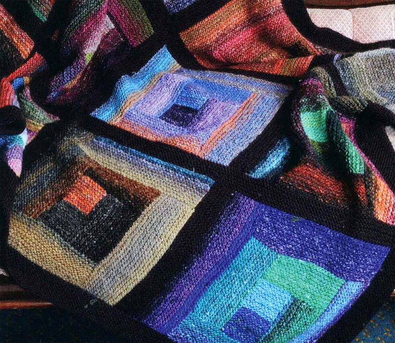 May include: A colorful knitted throw blanket with a geometric pattern of squares within squares. The blanket is made with a variety of shades of blue, green, purple, and orange yarn.