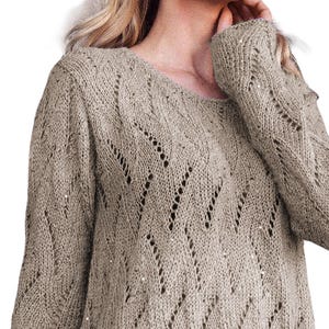 May include: A beige knitted jumper with a delicate openwork pattern. The jumper has long sleeves and a round neckline.
