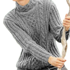 May include: A grey cable-knit turtleneck jumper. The jumper features a textured pattern and ribbed cuffs and hem. The sleeves are long, and the collar is a high turtleneck. The jumper is made of a thick, warm material.