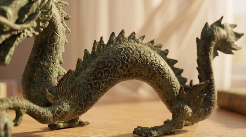 May include: A detailed bronze dragon sculpture with a textured surface. The dragon is in a curved pose, with its tail raised and its body arched. The sculpture is on a wooden surface.
