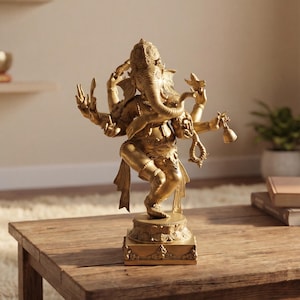 Op de afbeelding: Een gouden beeld van de hindoe-godheid Ganesha, met meerdere armen en een olifantenkop, staat op een houten tafel. Het beeld is gedetailleerd en lijkt van metaal te zijn. De achtergrond omvat een plank, planten en boeken.