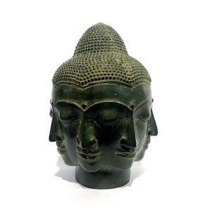 May include: A dark green, multi-faced Buddha head sculpture. The sculpture features four serene faces with closed eyes and a detailed, textured headdress. The bronze-like finish gives it an antique appearance, perfect for home decor.