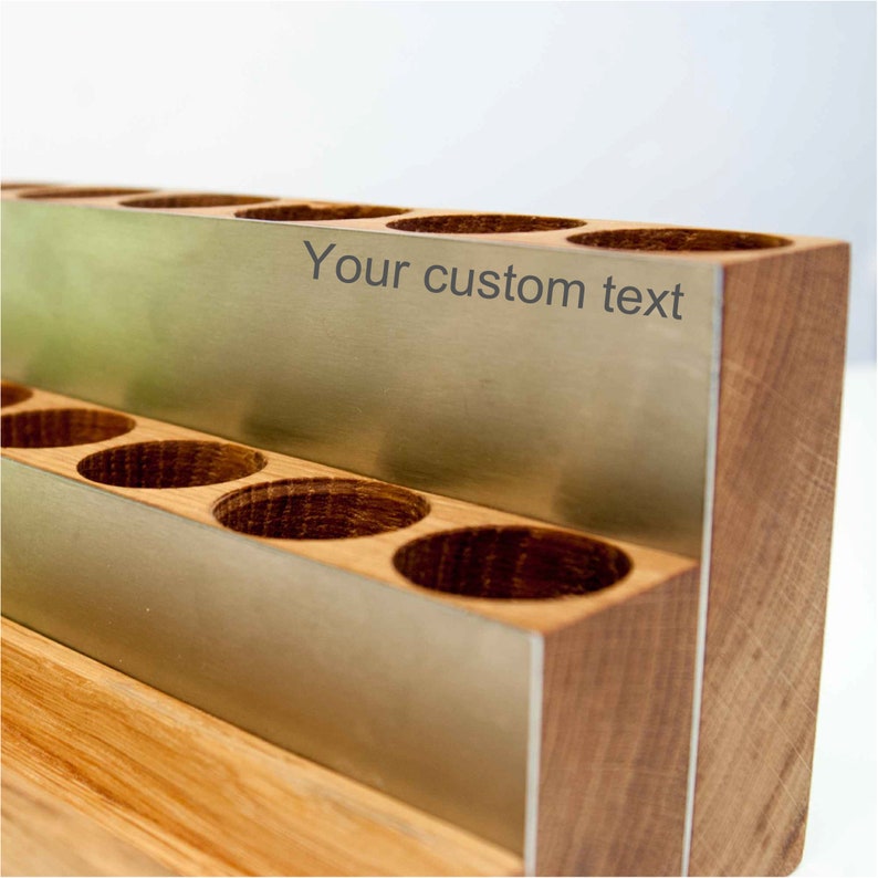 Puede incluir: Un organizador de madera con un inserto de metal y ranuras para guardar objetos peque&ntilde;os. El inserto de metal tiene el texto "Your custom text" grabado.