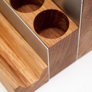Puede incluir: Organizador de madera con m&uacute;ltiples compartimentos, con un ribete de metal plateado. El organizador tiene un dise&ntilde;o escalonado con un estante inferior y una secci&oacute;n superior con cuatro aberturas redondas.