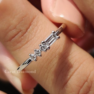 May include: A delicate silver ring with a row of small diamonds. The ring features three baguette-shaped diamonds and two round diamonds.