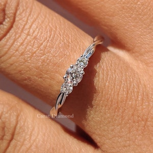 Può includere: Un delicato anello d'argento con tre piccoli diamanti rotondi incastonati in una fascia attorcigliata.